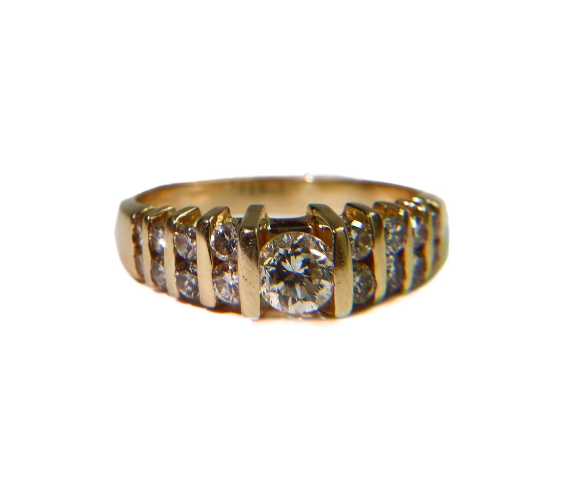 14k Yellow Gold and Multi-Diamond Ring Size 7: 14k Yellow Gold and Multi-Diamond Ring Size 7. 17 round cut diamonds in a channel setting weighing approximately 1.06 carats total with the center diamond weighing around 0.4 carats. Marked 14k. Weigh