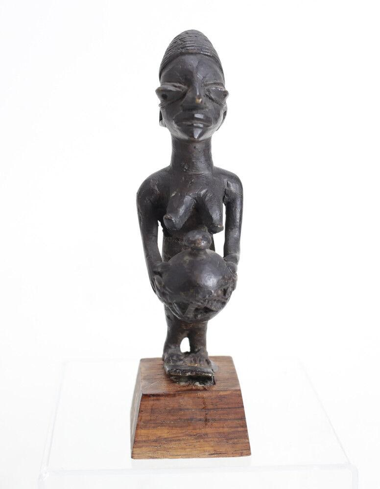 African Bronze Female figure Yoruba woman holding vessel: African Bronze Female figure, Yoruba woman holding vessel. Mounted on contemporary wood stand. .75lb Measurements: Approx. Figure 5.25" height. Condition: Condition commensurate with age, use. No note