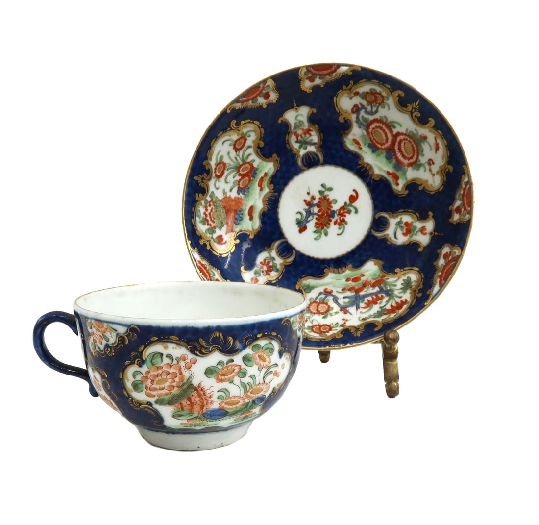Royal Worcester England Porcelain Cup and Saucer Florals circa 1770: Royal Worcester England porcelain cup and saucer Florals, circa 1770. Blue scale with gilt accents and hand painted red and orange florals throughout. Royal Worcester blue fret mark to underside. Weig