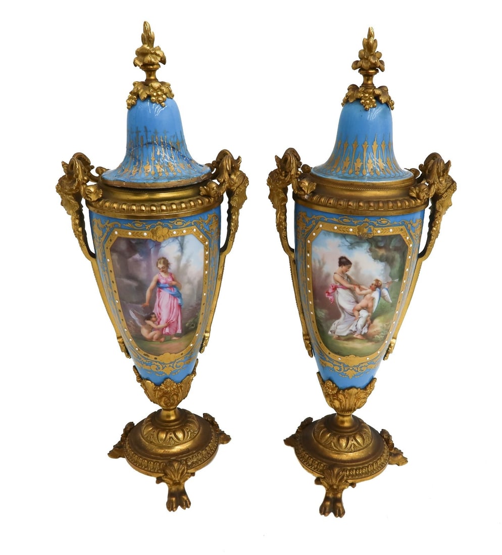 Pair Sevres Style Hand Painted Porcelain Twin Handled Covered Urns c1900: Pair Sevres style hand painted porcelain twin handled covered urns, circa 1900. A sky blue ground with gilt accents throughout. The center with hand painted scenes of beauties playing with cupid. Weig