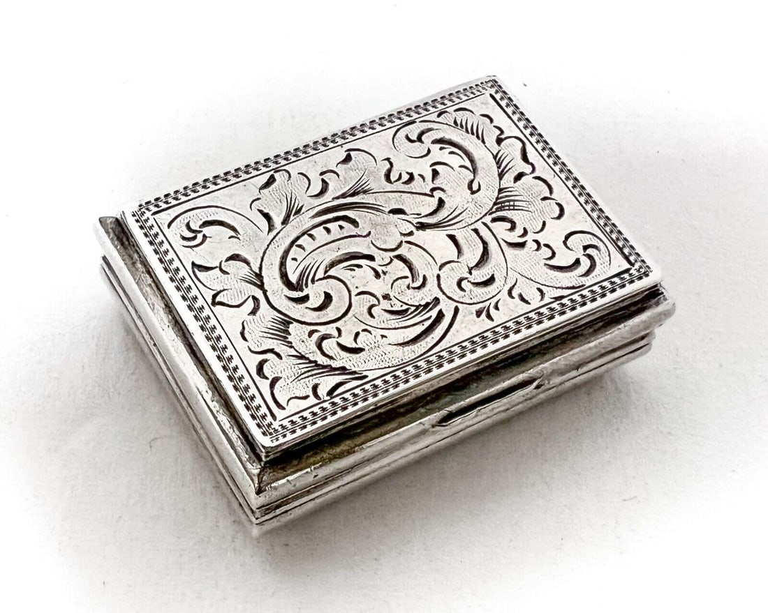 German 750 Silver Vinaigrette Box Kecker Before 1886: German .750 Silver Vinaigrette Box, Kecker. Before 1886. Finely engraved foliate and scroll designs, engraved foliate grill and gilt interior. Measurements: Approx. 9.46grams. 1.125 x 0.75 x 0.375 inc