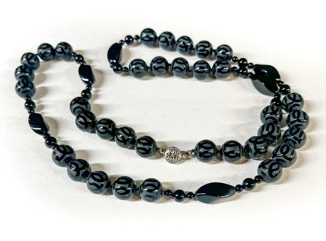 Vintage Etched Onyx Beaded Necklace 31": Etched Onyx Beaded Necklace, interspersed with swirled marquis beads; knotted; silver tone closure. c1990s. Measurements: Approx. 105.26grams total; 31 inches length; 11mm round beads, 20mm length mar