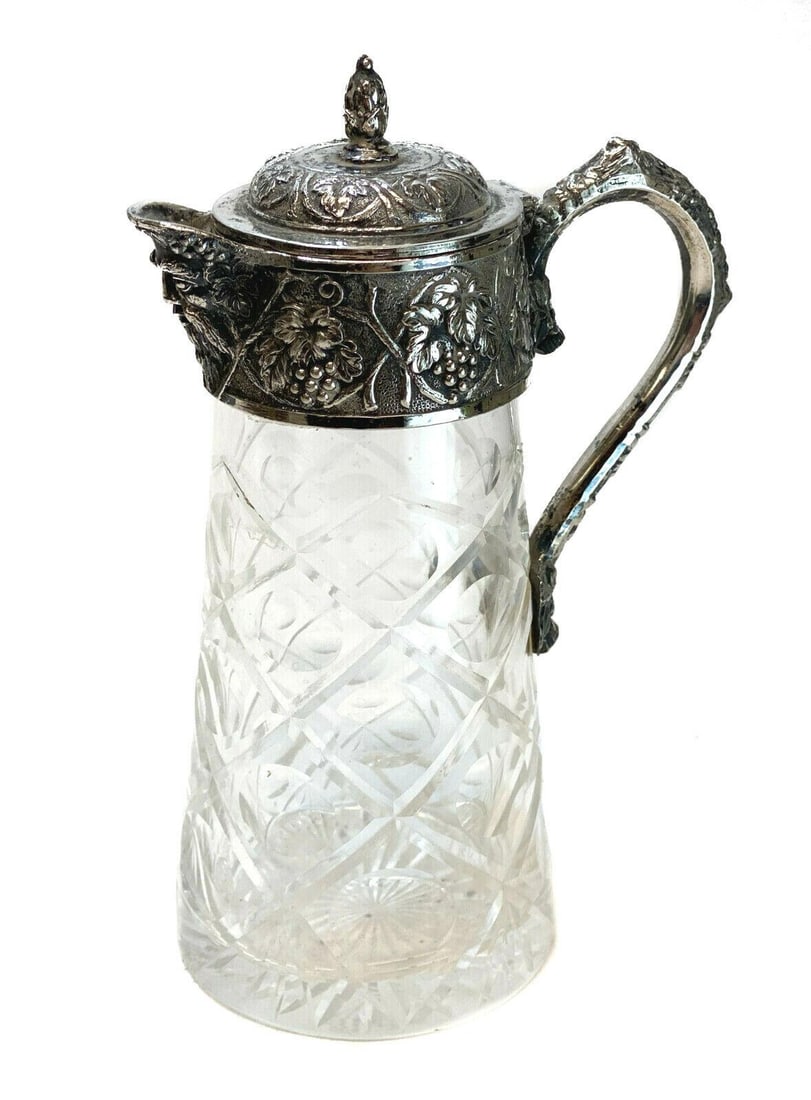Continental Silver Plate & Cut Glass Water Ewer Pitcher, circa 1900: Continental silver plate & cut glass water ewer pitcher, circa 1900. Hand etched diamonds cuts to the glass. Hand chased grapes, leaves, and vines to the handle and top rim. Weight: Approx. 1 lb Measu