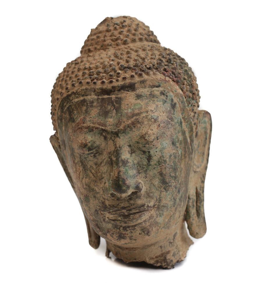 Thai Buddhist Bronze Head Fragment long pierced ear lobes: Thai Buddhist Bronze Head Fragment, long pierced ear lobes, closed or downturned eyes, long curved nose. Loss to the ushnisha. Band between hairline and forhead. 3.75lbs Measurements: Approx. 7" x 4.5