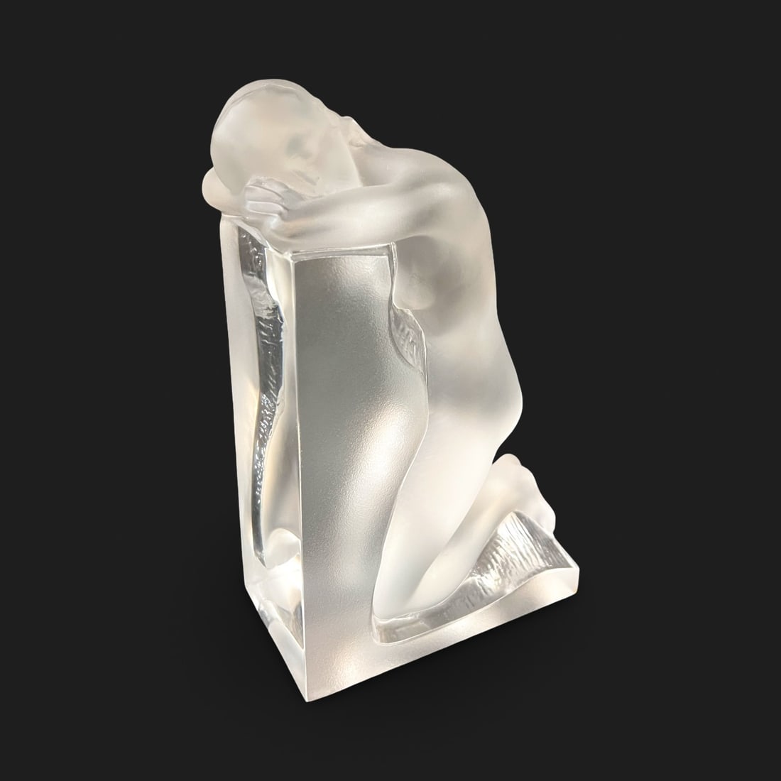 LALIQUE Reverie Kneeling Nude Crystal Bookend left: a single LALIQUE Reverie Kneeling Nude Crystal Bookend, heavy crystal piece with a nude figure kneeling, her head resting on her arms (facing to her left) Measurements: Approx. 8.75 x 4 x 5.5 inches C
