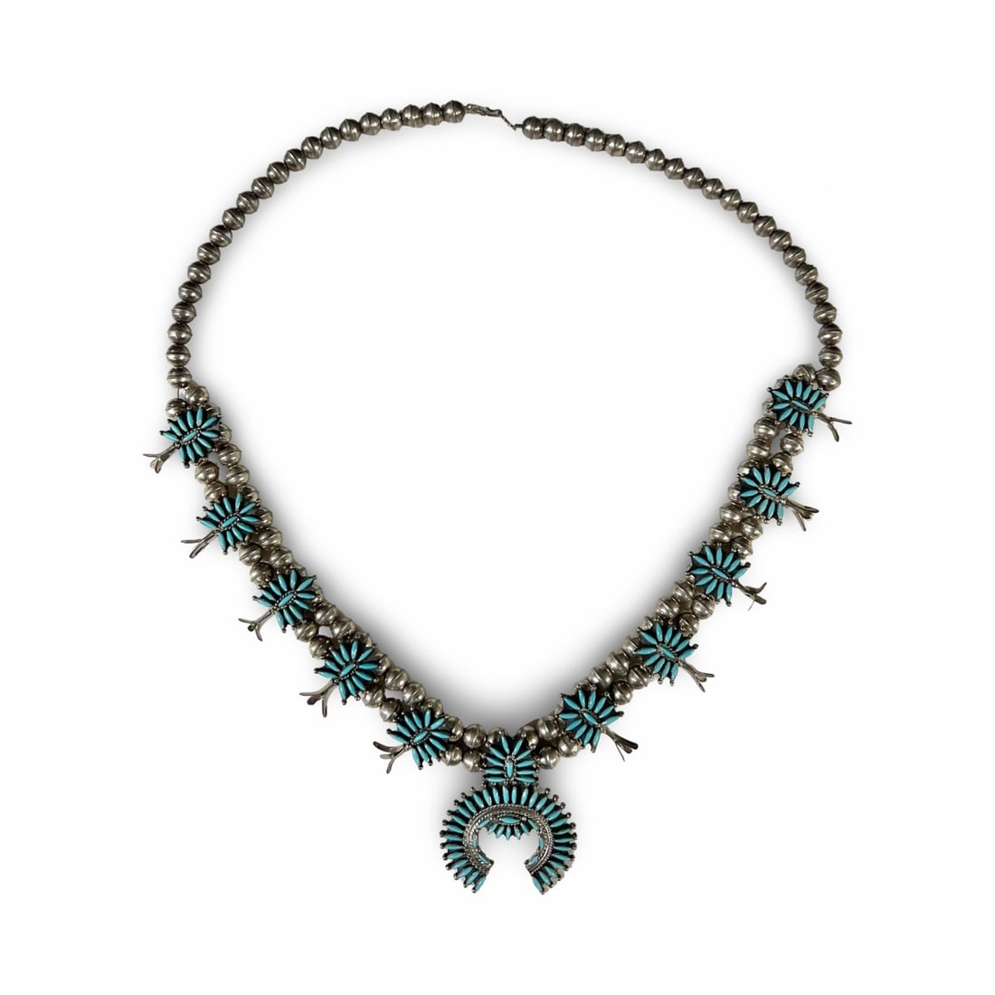 Native American Zuni Sterling Silver Turquoise Squash Blossom Necklace: Native American Zuni Sterling Silver Petit Point Turquoise Squash Blossom Necklace. Stunning blue stones set into the nala and blossoms. Double row of silver 'pearls' with ten blossoms, each side endi