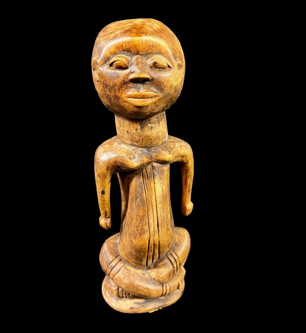African Wood Fetish Figure Congo: Central Africa Hand carved Wooden Fetish Figure, seated with legs crossed, scarification on stomach and legs. Label on underside states "Wabuye Tribe - Congo". Medium toned wood. Likely mid 20th Centu