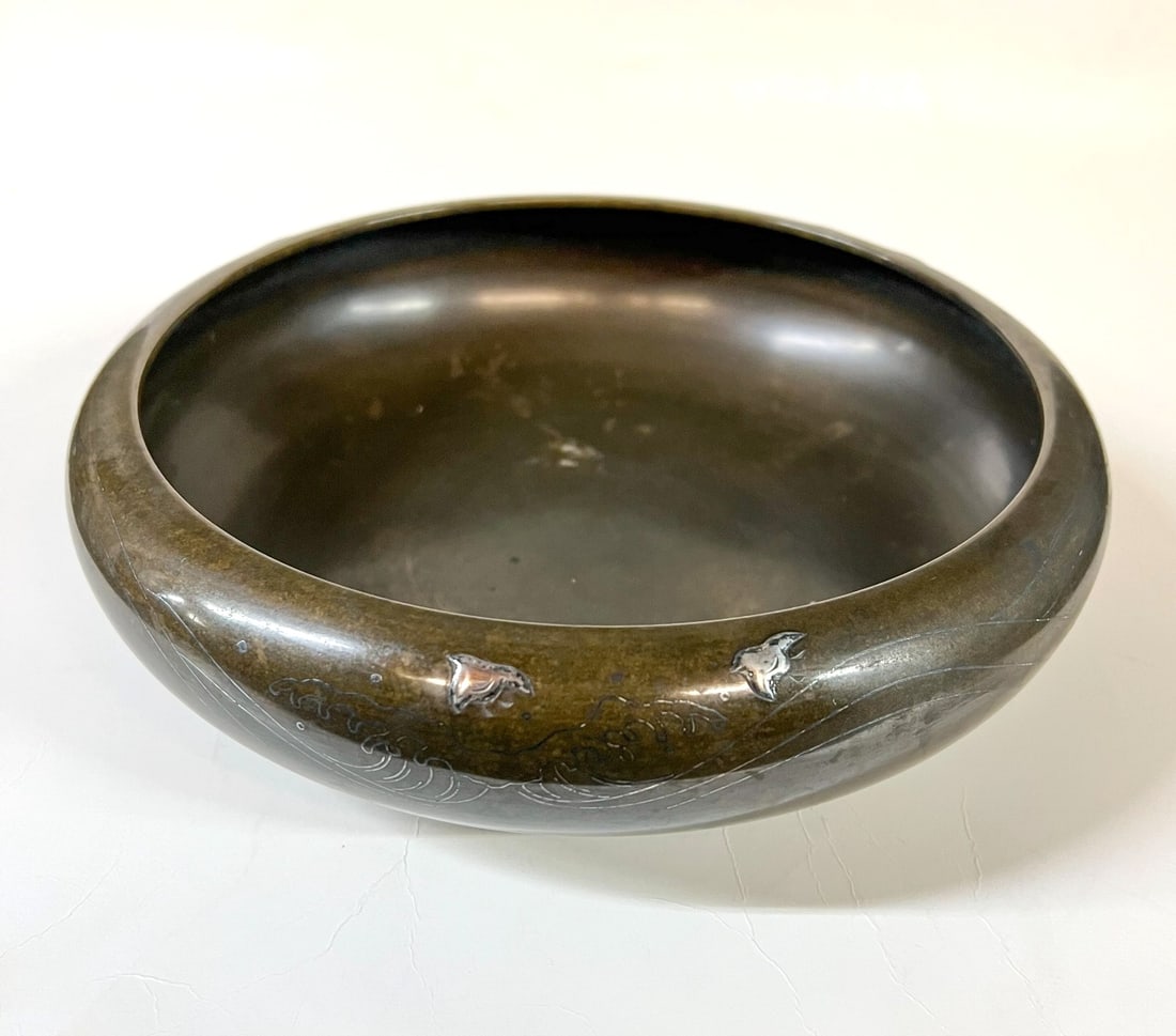Yoshimasa Japanese mixed metal bronze bowl Meiji period: Yoshimasa Japanese mixed metal shallow bronze bowl, likely Meiji period. Ocean waves with bright silver inlay with raised birds. Maker's mark on the underside. Measurements: Approx. 9.5 inches diamete