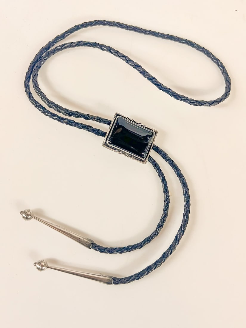 Vintage Jimmie Begay Navajo Bolo in Sterling Silver and Onyx silver tips: Vintage Jimmie Begay Navajo Bolo in Sterling Silver and Onyx, silver tips, c1970s. Makers mark on reverse and marked sterling. Back clip is not silver. Measurements: Approx. Main bolo piece is approx 