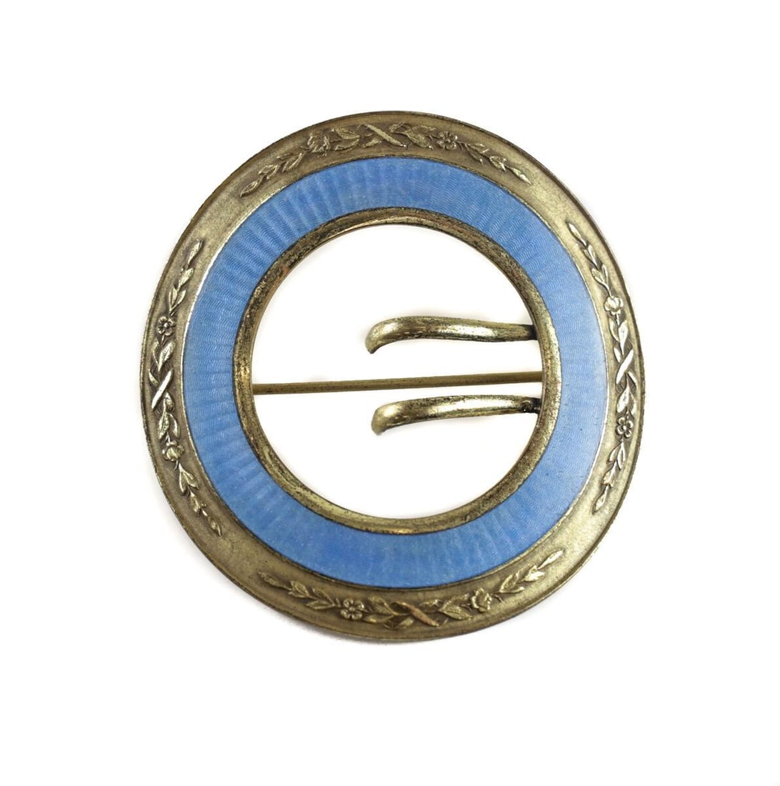 Blue Enamel Guilloche and Gilt Brass Circular Pin Brooch: A beautiful blue guilloche enamel and gilt brass brooch / pin. The outer rim of the pin has delicate hand chased florals and leaves. Indistinguishable maker's mark to the underside. Measurements: Appr