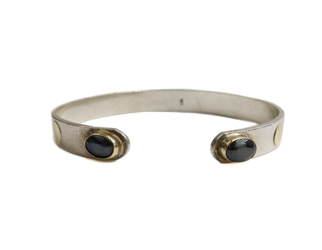 Sterling and 14k Yellow Gold Hematite Cuff Bracelet: Sterling and 14k yellow gold hematite cuff bracelet. Cabochon hematite jewels to edge. Marked 18k, but it is actually sterling silver and 14k gold. Weight: Approx. 16.11 grams Measurements: Approx. 6 