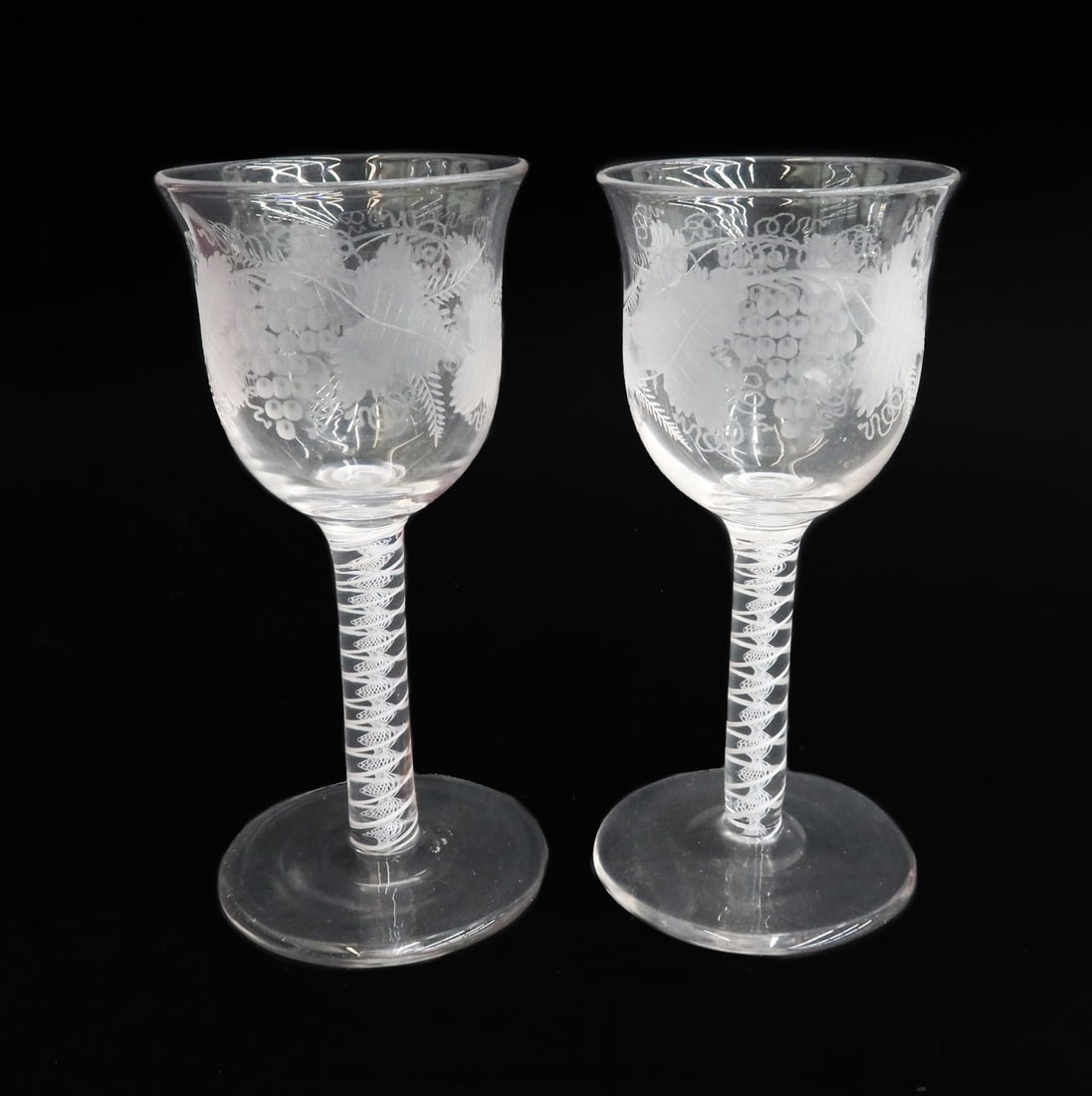 Pair English Georgian Air Twist Glass Wine Glass Goblets 19th Century or Earlier: Pair English Georgian Air Twist wine glass goblets, likely 19th century or earlier. Etched grape leaves and vines. White lattice striped air twist decoration to the stem. With polished pontil. Weight: