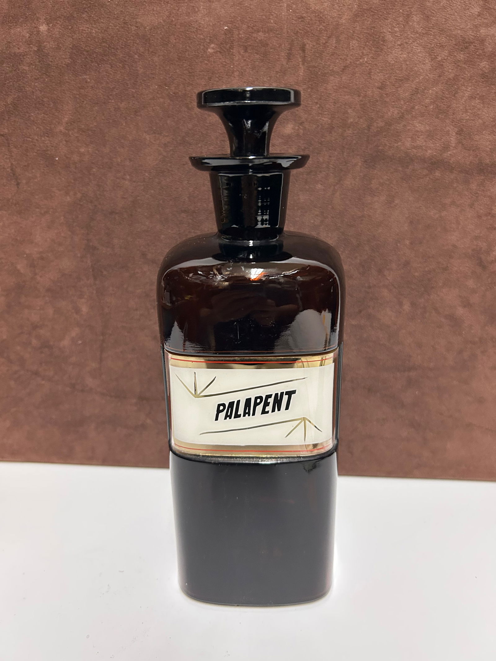Amber Glass Apothecary Bottle Labeled “PALAPENT”: This antique amber glass apothecary bottle measures 10 inches tall by 3 inches wide and dates to the late 19th to early 20th century, when pharmacists stored medicinal preparations in hand-labeled gla