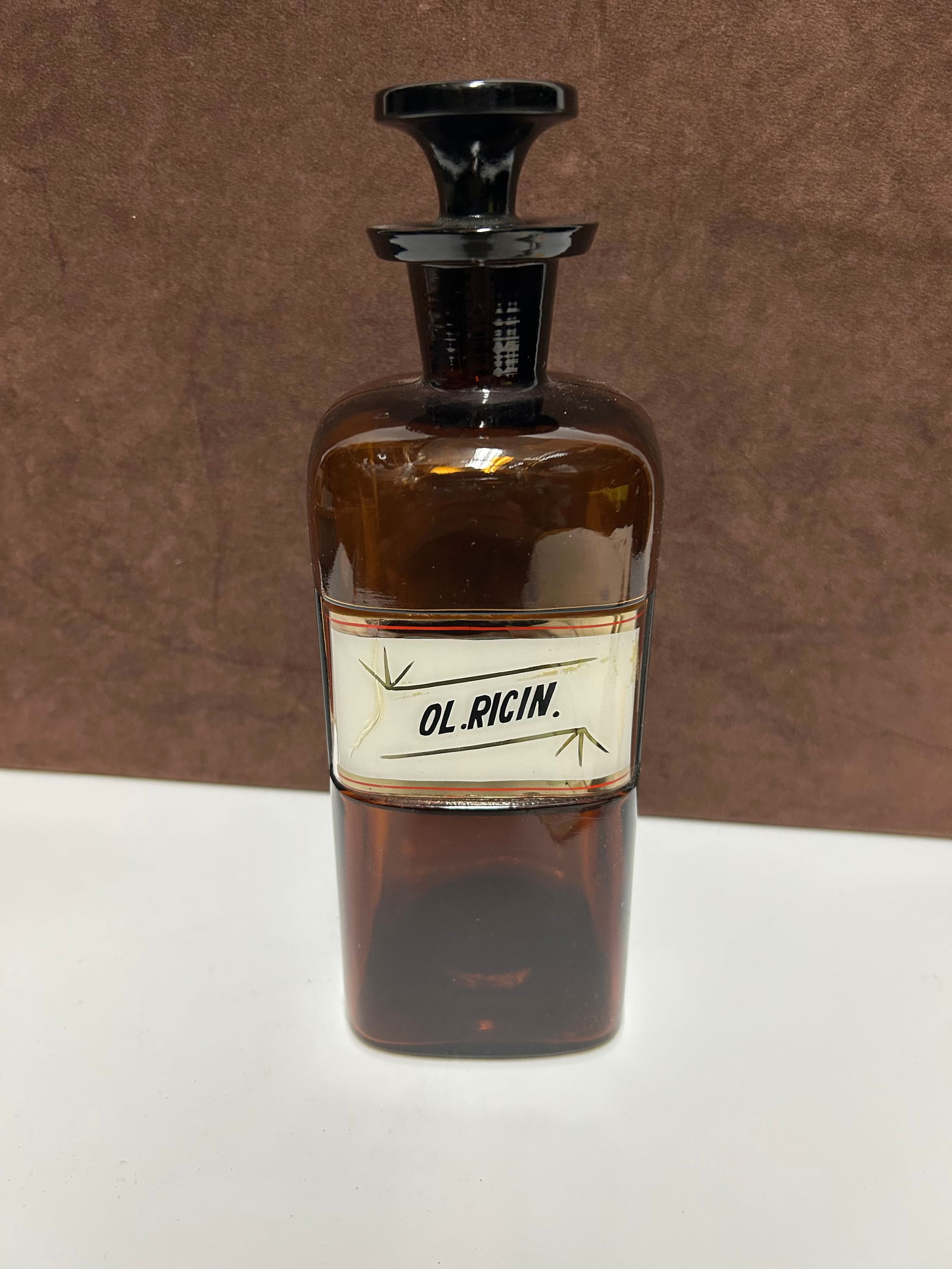 Amber Glass Apothecary Bottle Labeled “OL. RICIN.”: This antique amber glass apothecary bottle measures 10 inches tall by 3 inches wide and dates to the mid-to-late 19th century, circa 1850–1890. Crafted for early pharmacy use, it features deep amber