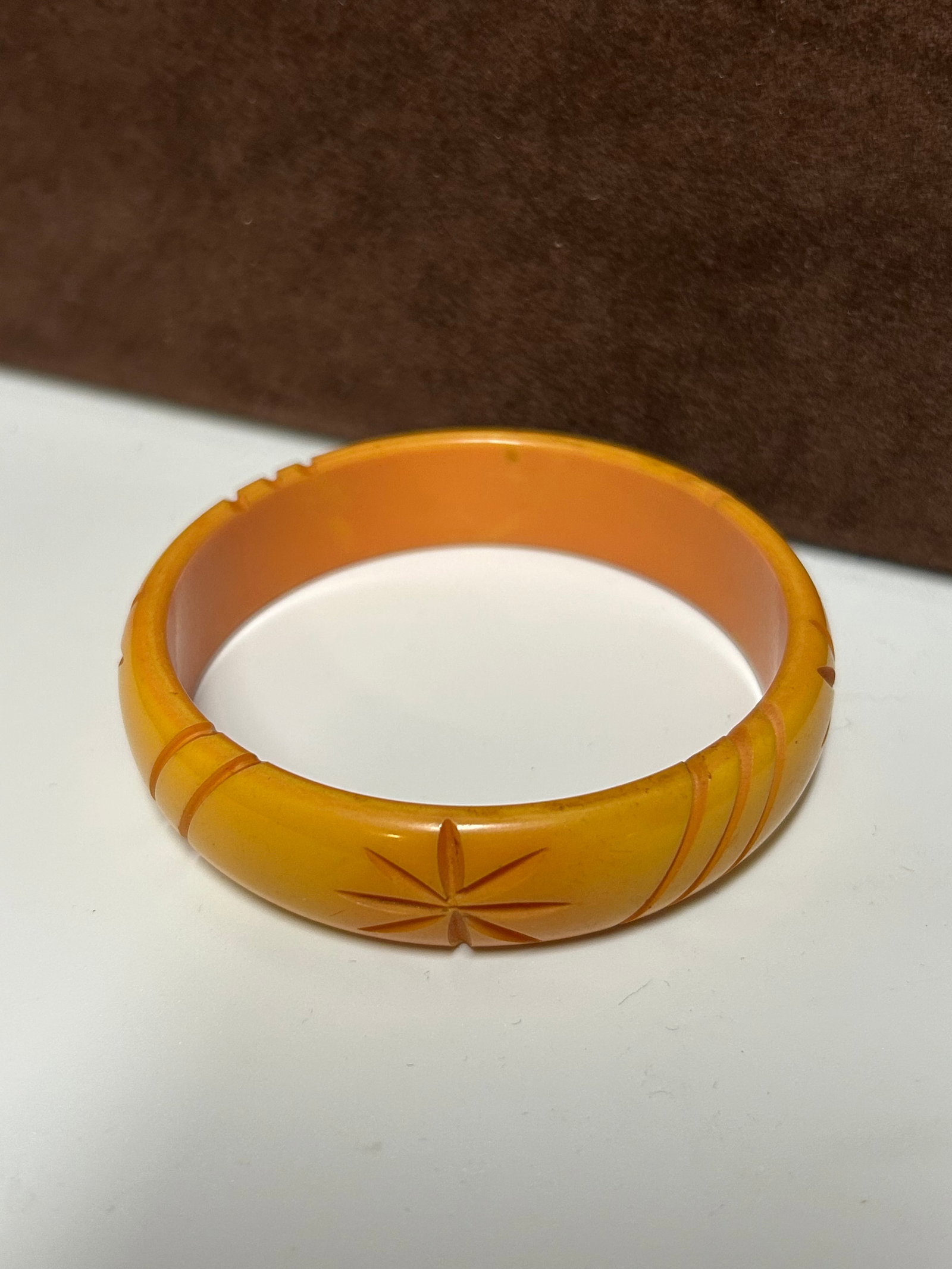 Vintage Carved Butterscotch Bakelite Bangle Bracelet with Floral Motif: This vintage carved Bakelite bangle dates from the mid-20th century and features the sought-after butterscotch coloration, displaying a warm blend of honey and amber tones. The bracelet is decorated w