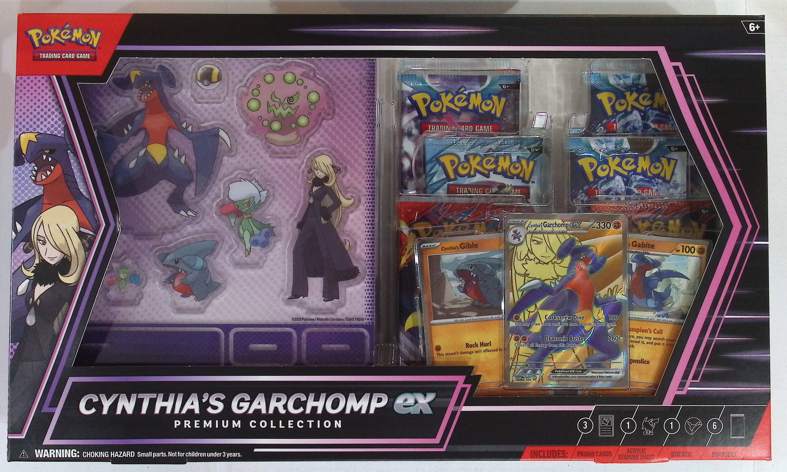 2025 Pokemon Cynthia's Garchomp ex Premium Collection Box: 3 Paradox Rift, 2 Destined Rivals, 1: 6 Booster Packs, 1 Full Art Foil Promo Card Featuring Cynthia's Garchomp ex, 2 Foil Cards Featuring Cynthias Gible & Cynthias Gabite, 1 Sheet of Acrylic Standees, 1 Double Sided Back-Drop Display, 1 P