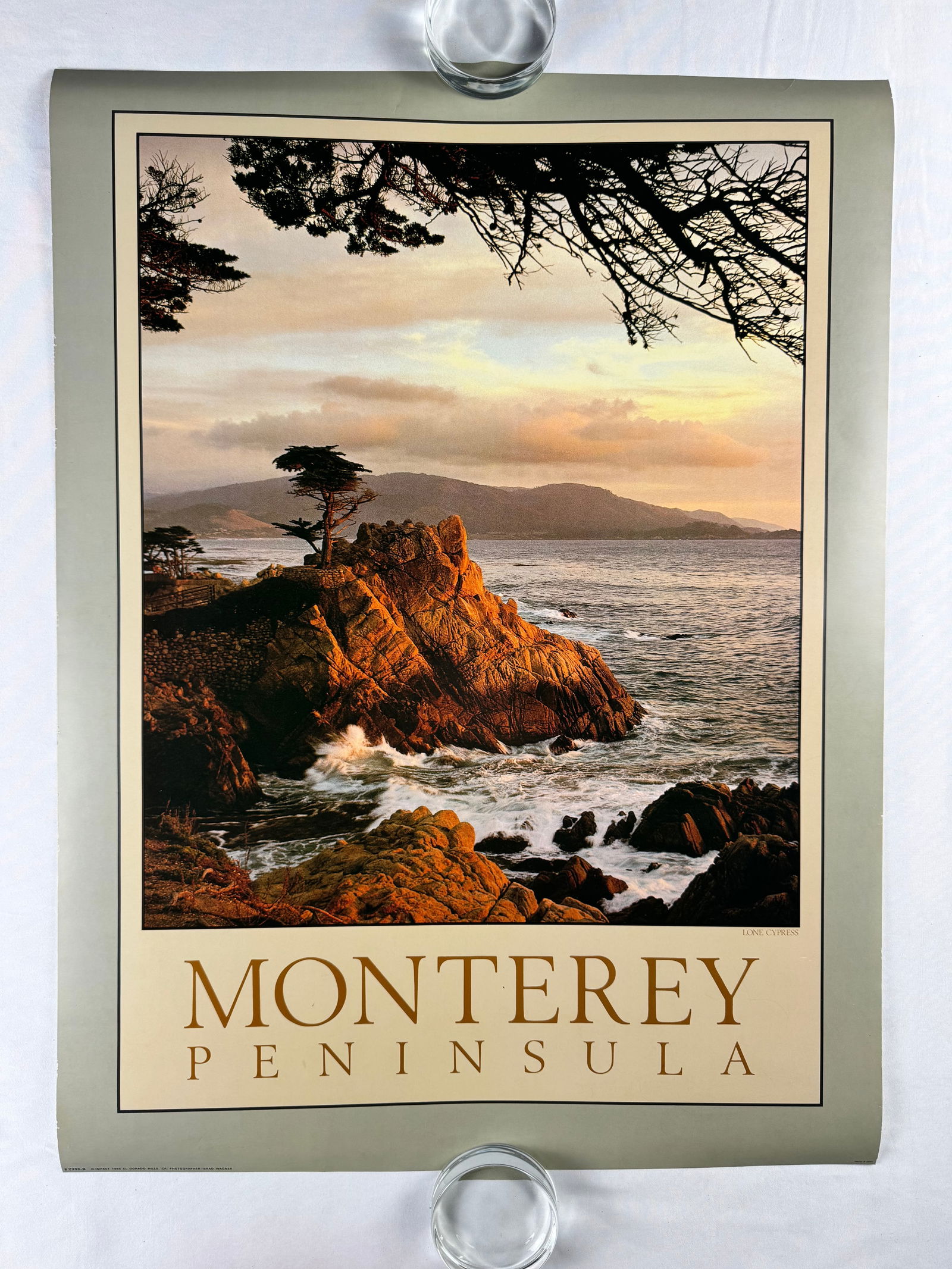 Vintage 1985 Monterey Peninsula Coastal Landscape Travel Poster by Brad Wagner: Travel poster featuring a coastal photograph of the Monterey Peninsula. © IMPACT 1985 EL DORADO HILLS, CA. PHOTOGRAPHER BRAD WAGNER