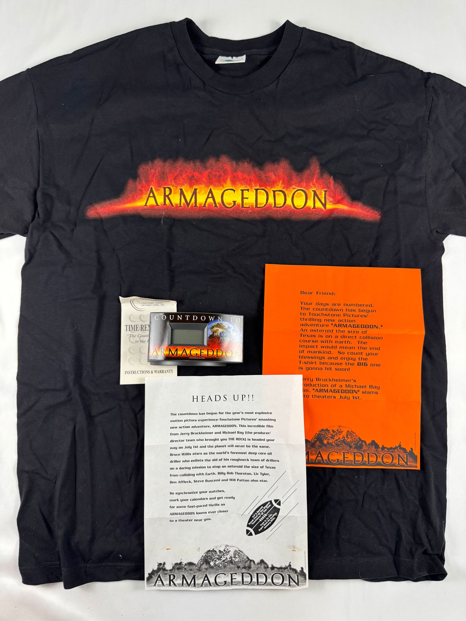 Armageddon (1998) Studio Promotional Press Release Tee Shirt Bruce Willis: A studio-issued promotional announcement for the film Armageddon, printed on folded paper with bold text; creases, small stains, and marks are visible from storage and age.