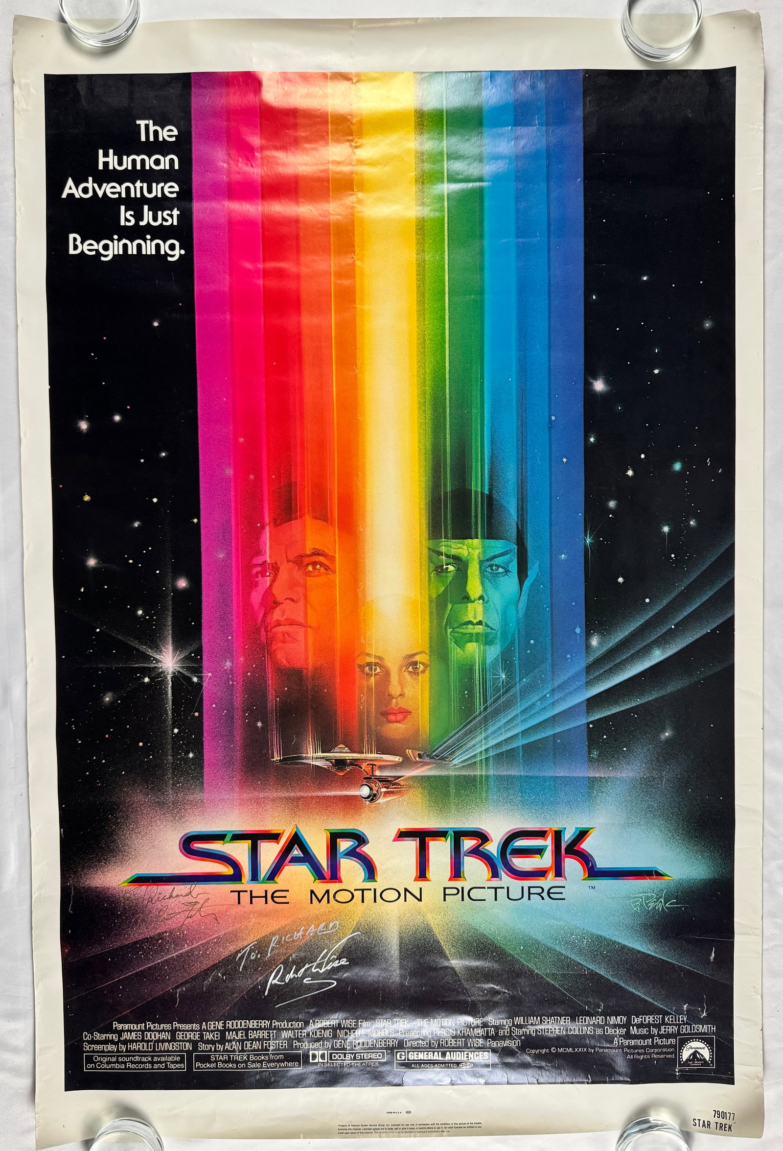 Star Trek The Motion Picture 1979 Poster Signed by Robert Wise and Alan Dean Foster: Poster for Star Trek The Motion Picture directed by Robert Wise. Stars William Shatner, Leonard Nimoy, and DeForest Kelley with rainbow beam design. Signed by Director Robert Wise and Writer Alan Dean
