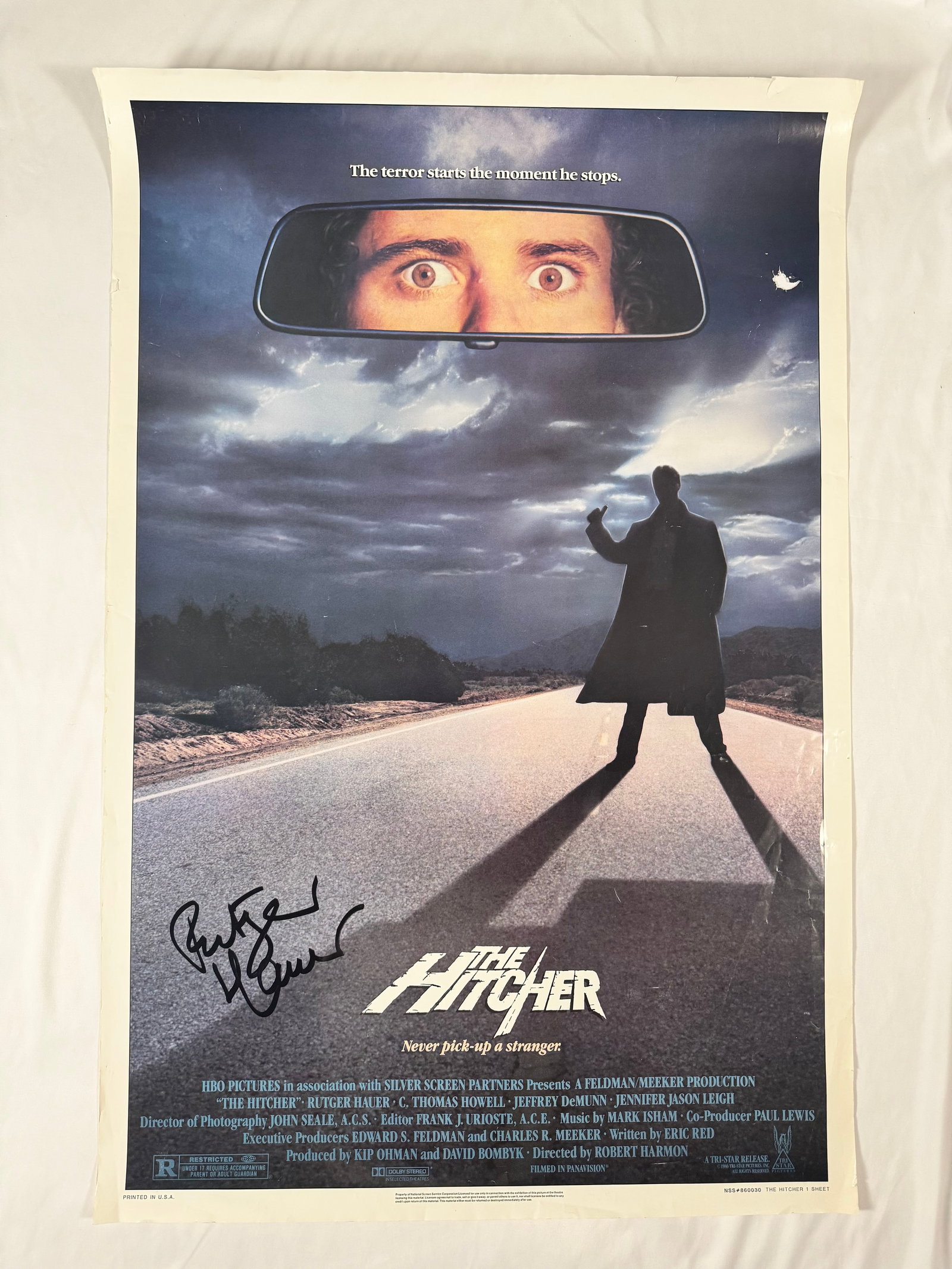 The Hitcher 1986 Signed by Rutger Hauer Original 27x41" One Sheet 1SH Movie Poster: The Hitcher is a 1986 American horror thriller film directed by Robert Harmon and written by Eric Red. It stars Rutger Hauer as the title character, a murderous hitchhiker who stalks a young motorist
