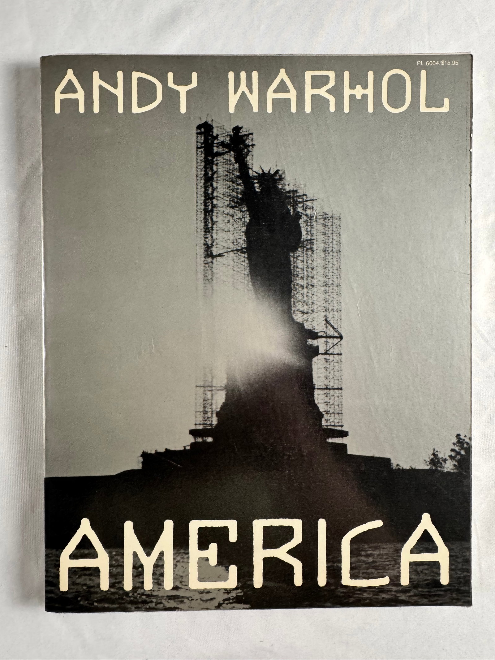 Andy Warhol America Softcover Exhibition Catalog PL 6004: Softcover exhibition catalog titled America by Andy Warhol. Cover marked PL 6004 with printed retail price $15.95.