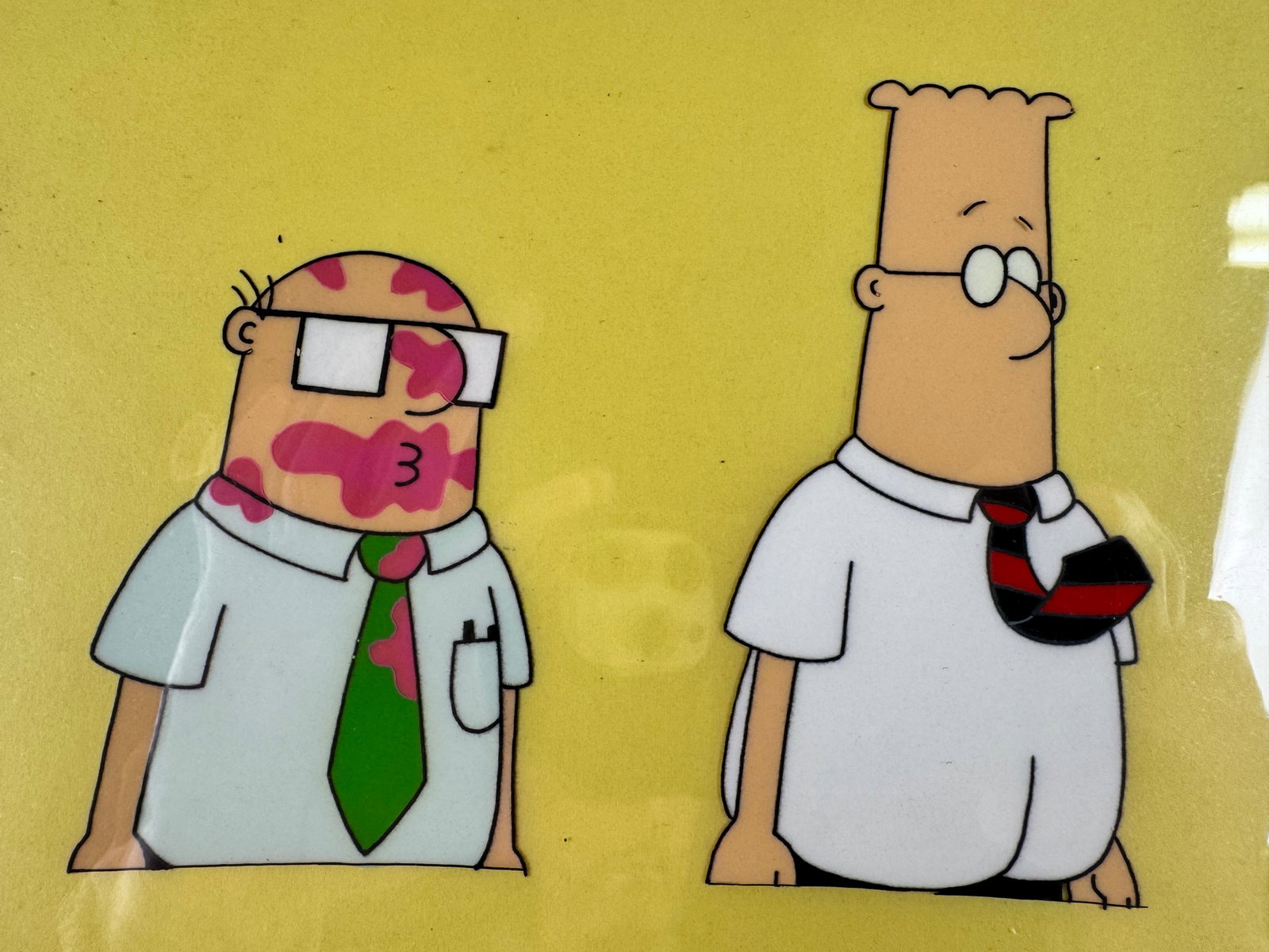 Dilbert Original Animation Production Cel Dilbert and Dogbert Signed Seth Kearsley COA: This original animation production cel depicts Dilbert and Dogbert against a yellow background. The cel is signed by Seth Kearsley and includes a certificate of authenticity.