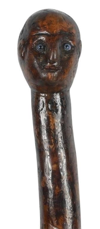 Wood Cane with Head: Wood Cane with Head. Potentially initialed below head. Wooden carved cane. Interesting folk art cane with a head and glass eyes. There is a small human face along with a cat face carved into the knots