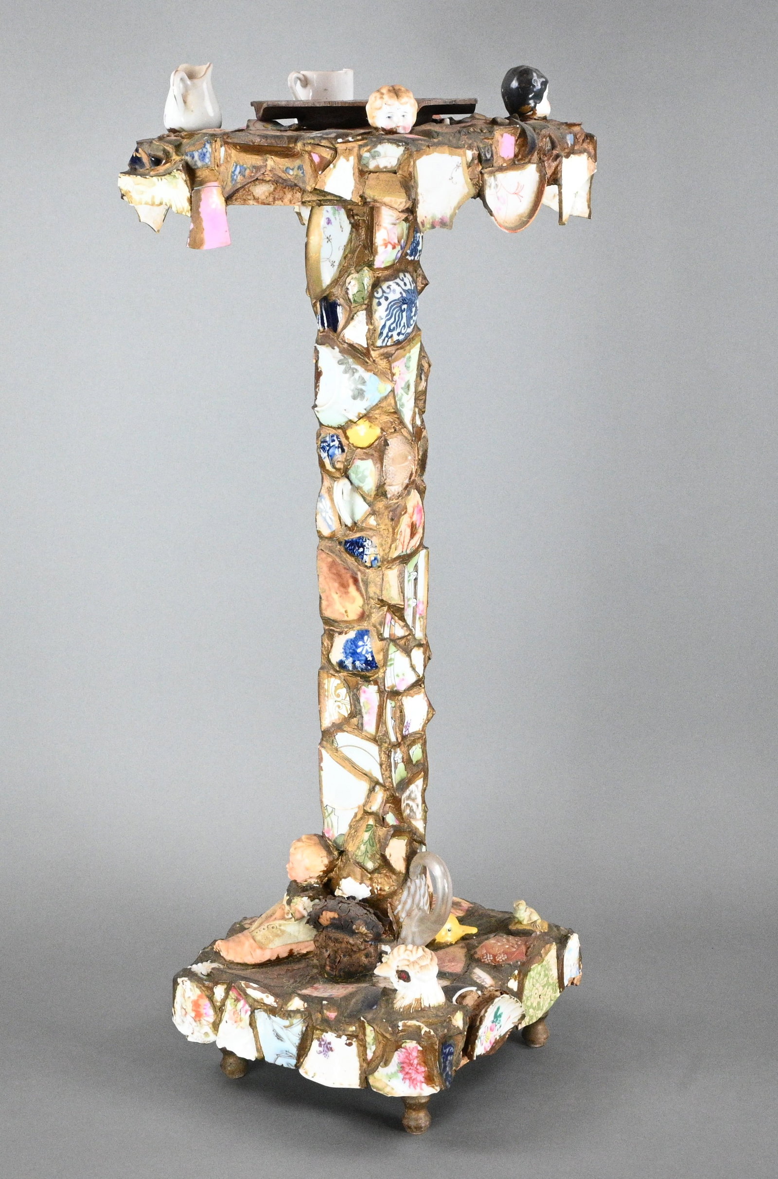 Memory Ware Pedestal: Memory Ware Pedestal. Covered with a particularly rich variety of shards from very fine China, as well as doll heads, baby figurines, patterned glass, a China frog and rooster's head, a lady's watch,