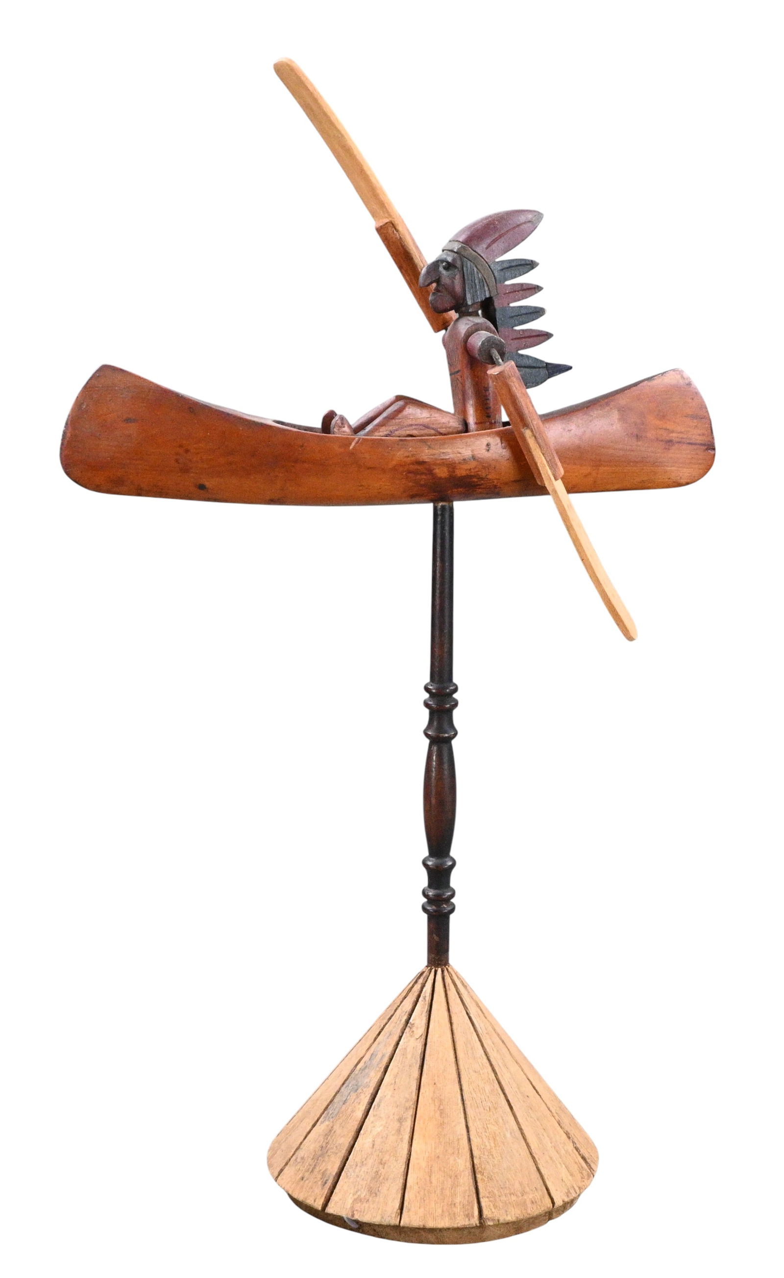 Native American Canoe Whirligig Figure: Native American Canoe Whirligig Figure. A hand carved fold art whirligig depicting a Native American paddler seated in a long shallow canoe mounted on a thin turned dark colored wooden shaft with a