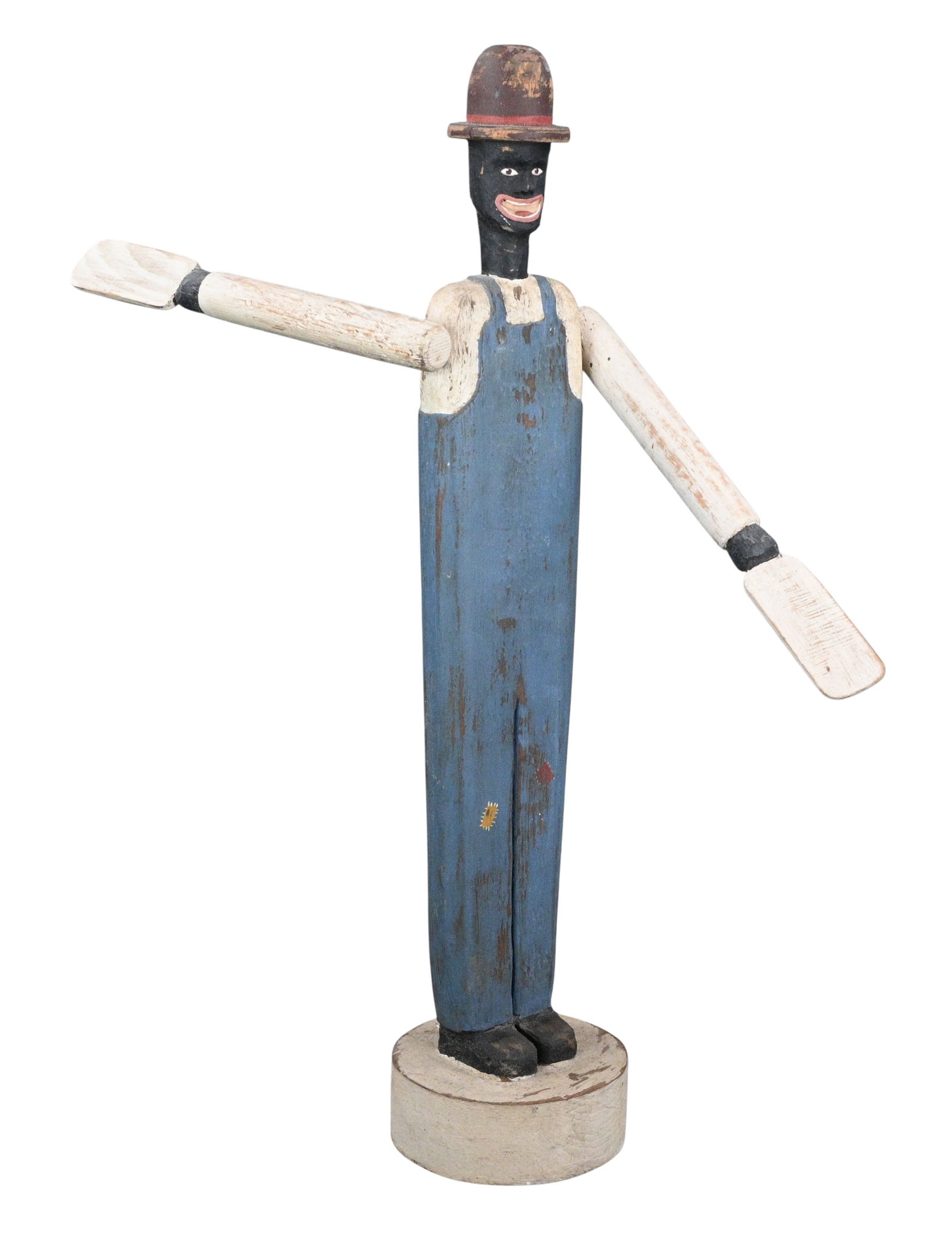 Black Folk Figure in Blue Overalls with Moving Arms: Black Folk Figure in Blue Overalls with Moving Arms. 1985. Signed and Dated. Carved and painted wooden Black folk figure with articulated arms, wearing blue overalls and a top hat, mounted on a