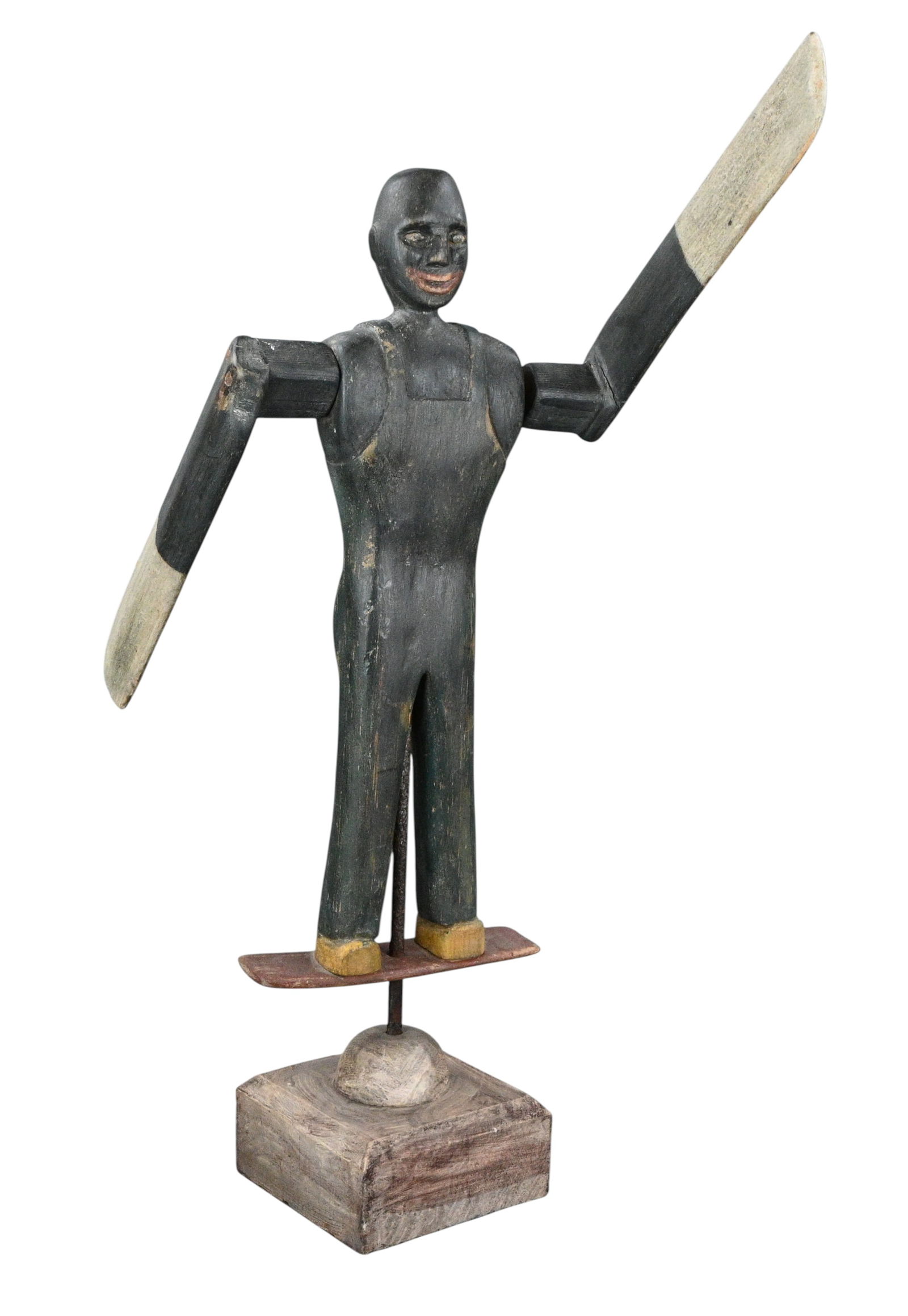 Black Articulated Folk Figure with Paddle Arms: Black Articulated Folk Figure with Paddle Arms. Carved and painted wooden folk figure with articulated arms ending in elongated paddle like forms. The figure stands on a platform mounted to a