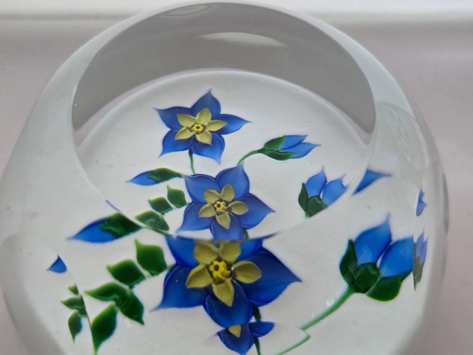 Caithness "Blue Spray": 1986 weight by Allan Scott for Caithness in 1986. A spray of blue and yellow flowers and buds lie on a snow white ground. Only 100 made.Diam: 70mm or 2 3/4 ins
