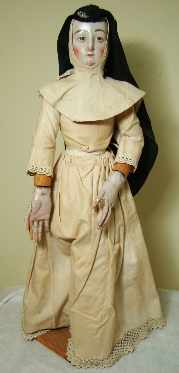 Colonial Period, a tall "santos" or religious doll: Colonial Period, a tall "santos" or religious doll. A tall standing wooden nun wearing pale yellow dress and black habit veil. Her arms and face in realistically rendered wood with her hands being art