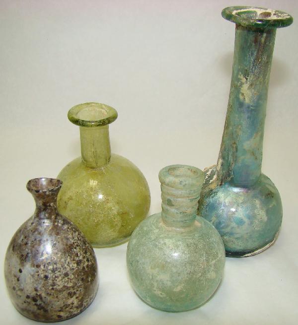 Roman, c. 100-300AD., a lot of 4 small flasks: Roman, c. 100-300AD., a lot of 4 small and choice flasks. 3 are small with mostly round bodies. The tallest has long tubular neck with short "bell" shaped body and some encrustation at one side of bod