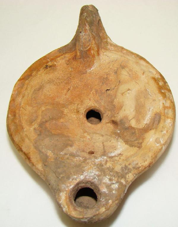 Roman, c. 100-300AD., a nice "discus" lamp: Roman, c. 100-300AD., a nice "discus" type terra cotta oil lamp with a dog to the left of a standing boy. In stained mottled earth tones. Intact and attractive with loop handle at back. . L: 4.5". Pie