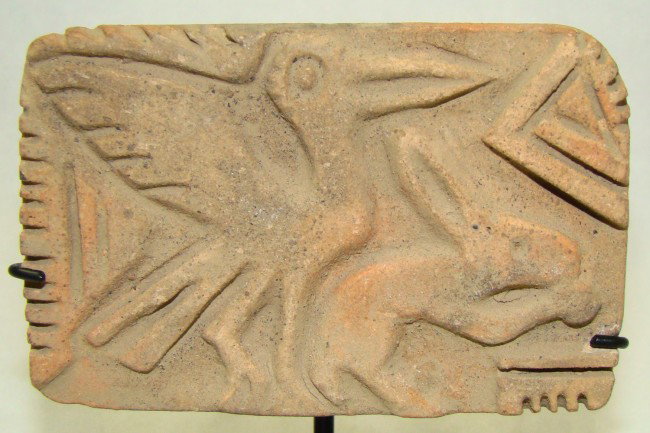 Ecuador,"Bird of Prey" ceramic textile stamp.: Ecuador, Jamacoaque, 200-600 AD. "Bird of Prey" ceramic textile stamp. Large bird prepares to swoop down on unsuspecting hare. Pinch handle on back. S: 3.25" x 2". Mounted on custom stand. Old San Fra