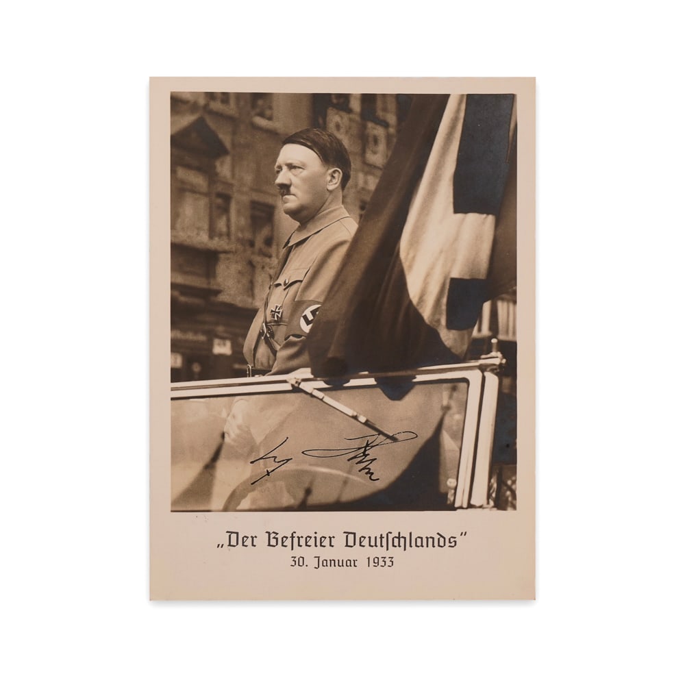 ADOLF HITLER SIGNED "DER BEFREIER DEUTSCHLANDS" POSTCARD, DATED JANUARY 30, 1933: 5 7/8 x 4 1/8 in (14.8 x 10.5 cm) This historically charged artifact features a real photo postcard depicting Adolf Hitler standing in an open car, emblazoned with the title "Der Befreier Deutschlands