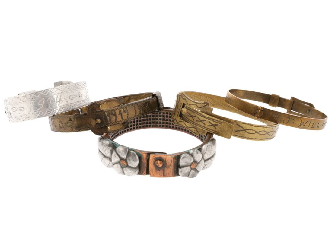 WWI Trench Art Bracelet Lot: WWI Trench Art Bracelet Lot Five bracelets of various materials, most resembling belts with buckles. 1) Heavy bracelet made from the copper driving band of an artillery shell has applied aluminum flow
