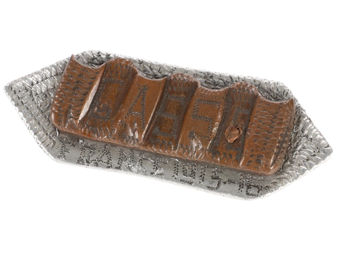 WWI Soldier's Souvenir Trench Art Brooch - CASSE: WWI Soldier's Souvenir Trench Art Brooch - Casse 40 x 15mm segment of an artillery shell driving band is engraved with the surname CASSE. It's mounted on an elongated hexagon of sheet aluminum etched 