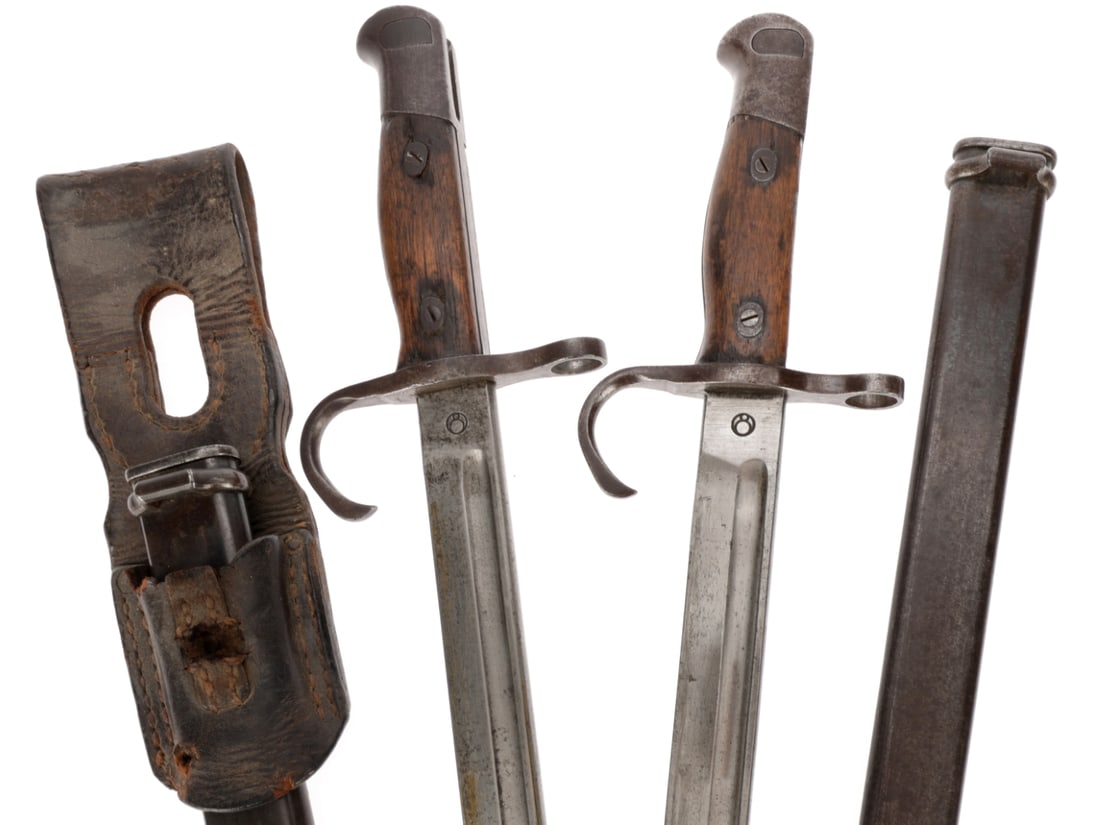 WWII Japanese Bayonet Lot: WWII Japanese Bayonet Lot Two Type 30 bayonets with scabbards, one with leather frog, the other without. Nagoya Arsenal Type 30 bayonet, fullered blade is finished bright, evenly scattered with dark a