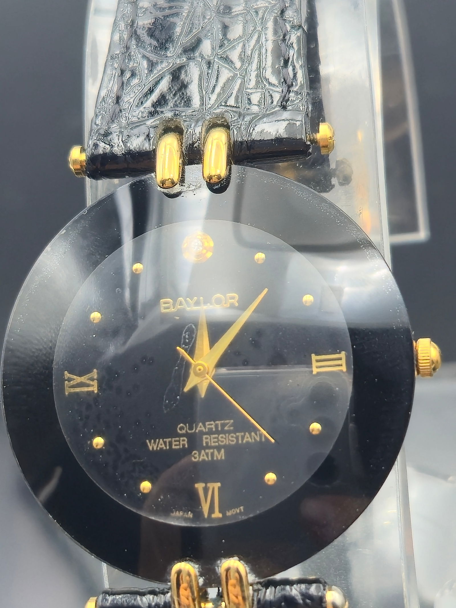 Baylor Quartz Dress Watch – Black & Gold Minimalist Design: This Baylor wristwatch exudes minimalist elegance with its ultra-slim black case and contrasting gold-tone accents. The dial features simple dot and Roman numeral hour markers at 3, 6, 9, and 12 o’c