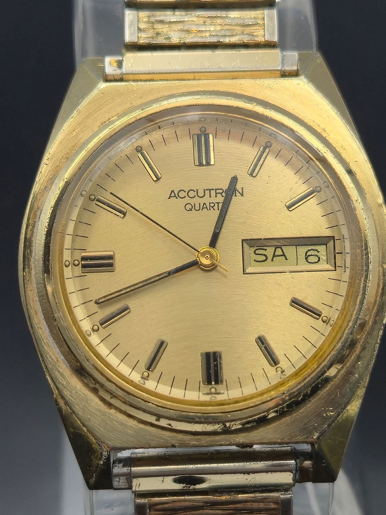 Vintage 1980 Bulova Accutron Quartz Watch (P0) – Gold Tone Day-Date: This 1980 Bulova Accutron Quartz (date code P0) is a stylish example of early quartz innovation paired with timeless design. Featuring a brushed champagne dial, gold-tone stick markers, and a sharp an