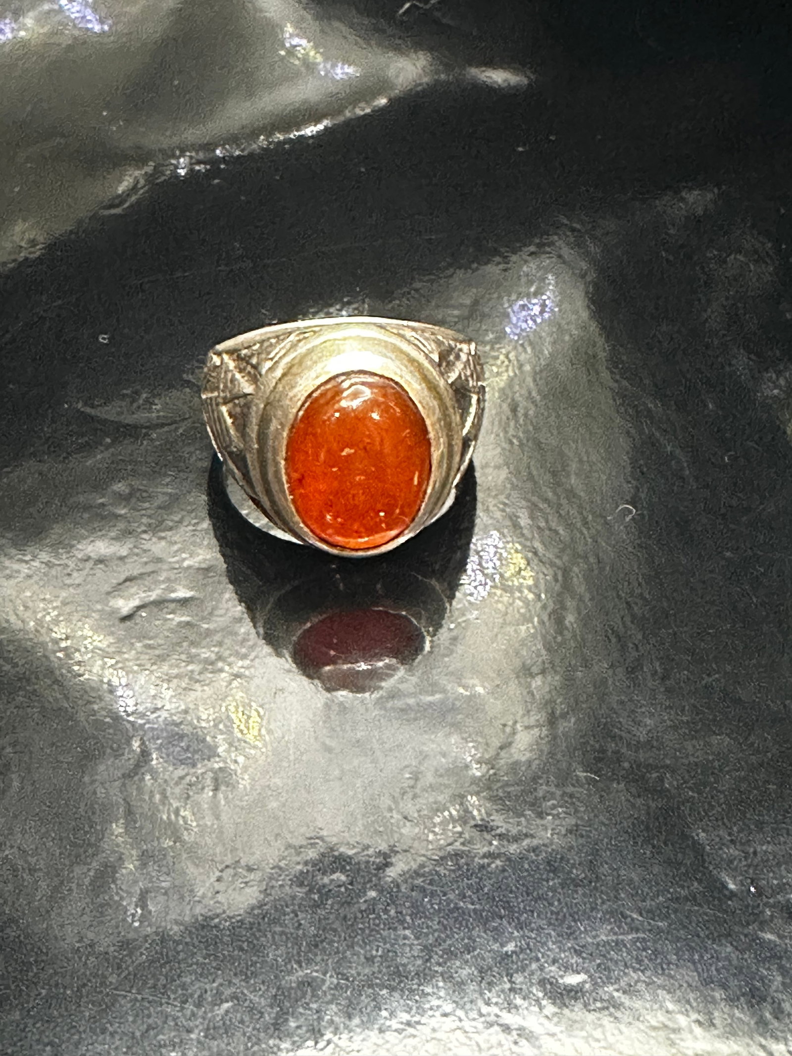Vintage Sterling Silver Ring with Orange Cabochon Stone and Etched Design: Offered here is a bold vintage sterling silver ring featuring a vibrant orange cabochon stone set in an oval bezel. The ring showcases detailed etched designs along the shoulders, adding visual intere