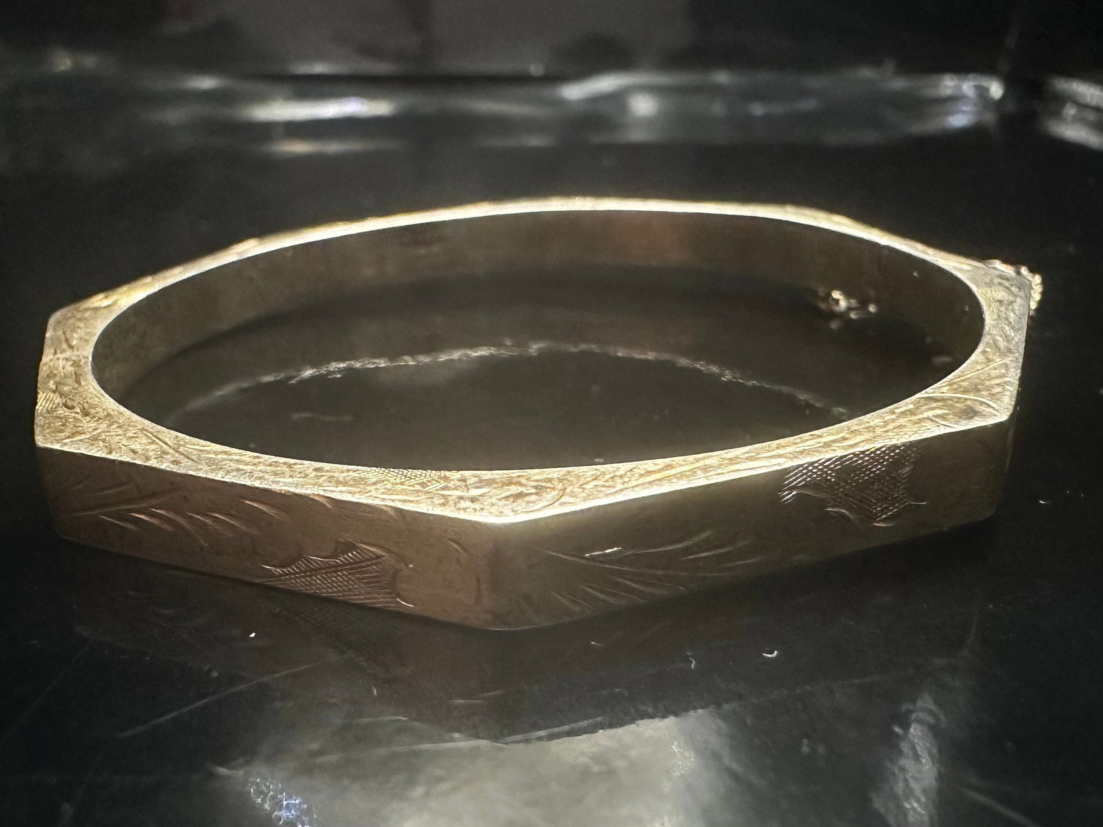 Vintage Sterling Silver Octagonal Bangle Bracelet: Offered here is a beautifully hand-engraved vintage bangle bracelet crafted in sterling silver. The piece features an elegant octagonal shape with detailed etched floral and foliate motifs around the 