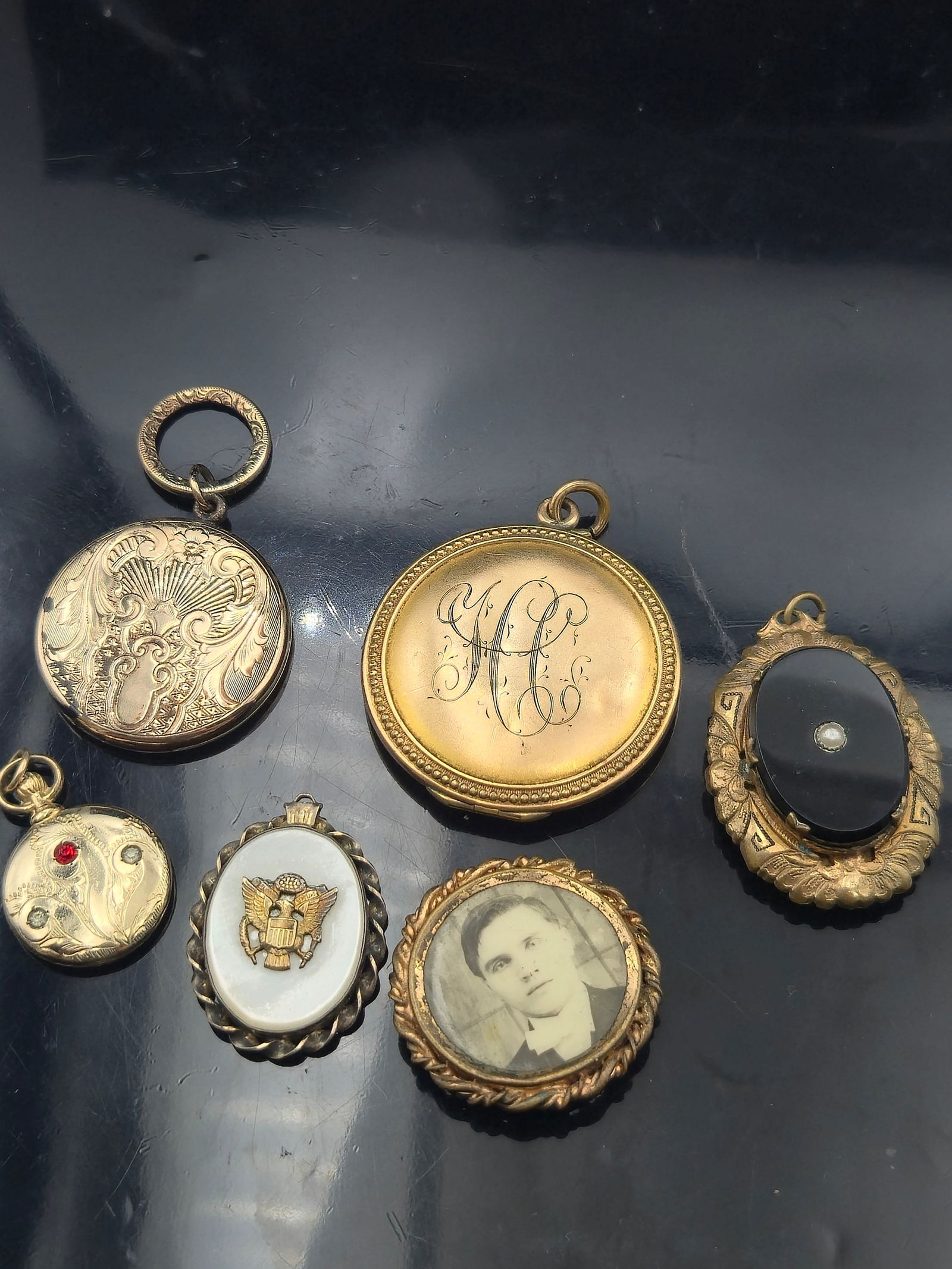 Lot of 6 Antique & Vintage Lockets & Pendants – Military, Portrait, Mourning, 12K GF on Sterling: A diverse lot of six antique and vintage lockets and pendants, spanning early to mid-20th century styles. Includes military-themed, mourning, portrait, and engraved designs. One piece is a 12K gold-fi
