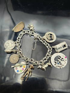 Vintage Sterling Silver Charm Bracelet – 43.2g – 10 Charms – Art, Travel, and Zodiac Theme: This vintage sterling silver charm bracelet features a variety of unique and eclectic charms with artistic, astrological, and international travel motifs. Weighing 43.2 grams, the bracelet is secured
