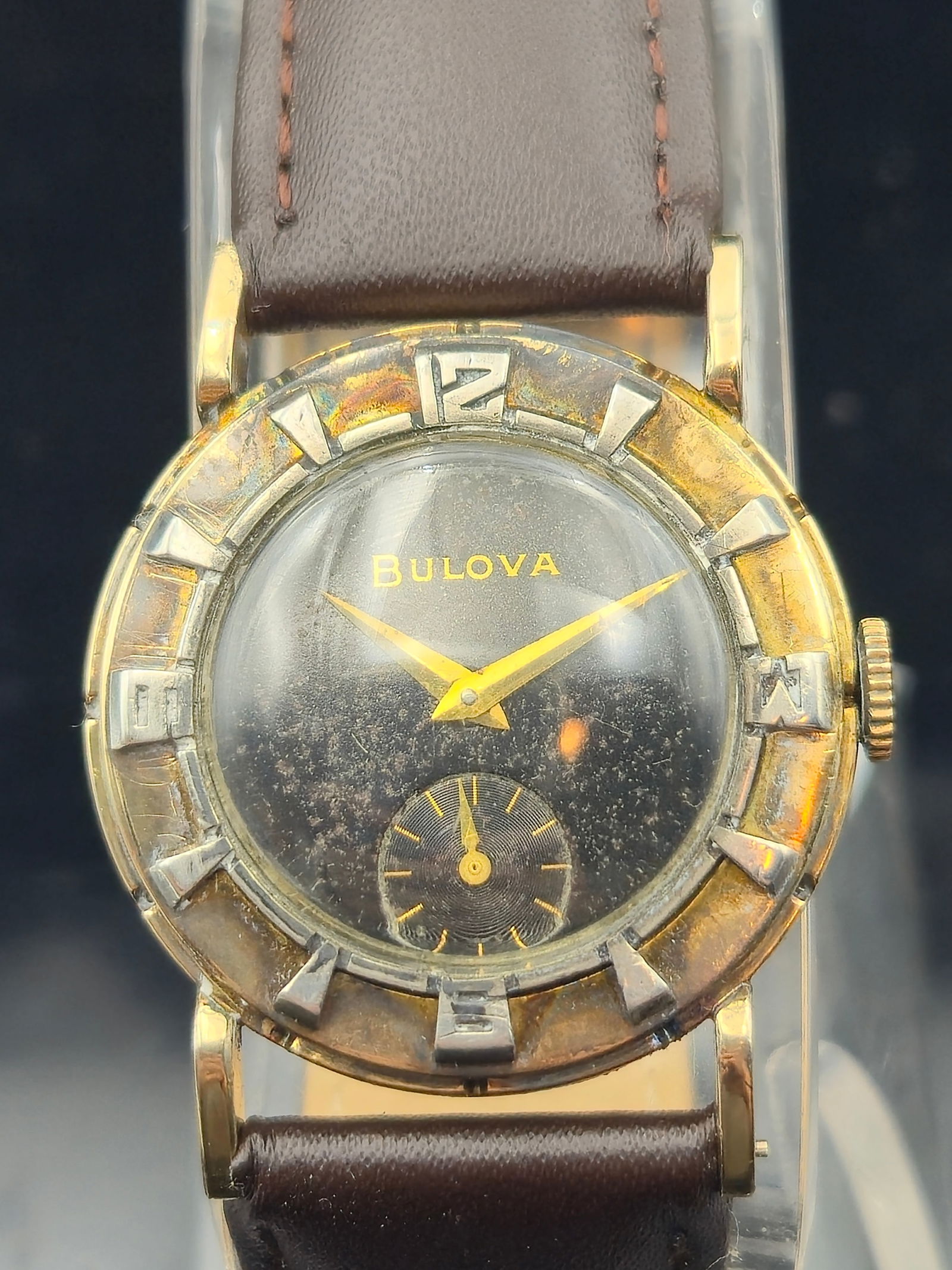 1953 Bulova "Berkshire" 10K RGP Men's Watch – 17J Manual Wind Cal. 10BT: This vintage 1953 Bulova "Berkshire" features a striking black dial with gold-toned dauphine hands and raised hour markers in a unique sculpted bezel. Housed in a 10K rolled gold-plated case (serial 6