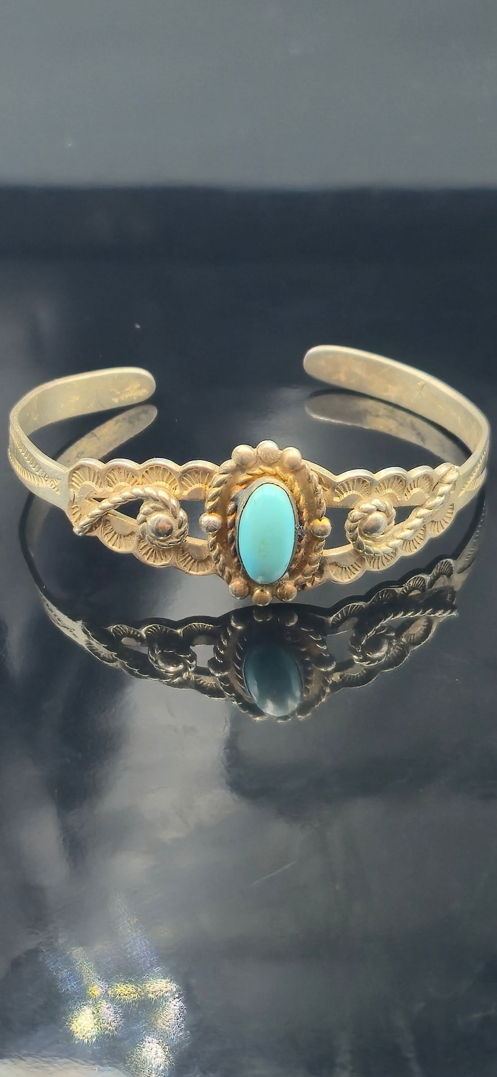 Vintage Navajo Turquoise Cuff Bracelet 9.7g: This vintage Navajo-style cuff bracelet is crafted in an intricate stamped and scalloped sterling silver design, centered with an oval-cut turquoise cabochon in a traditional rope and bead setting. Th