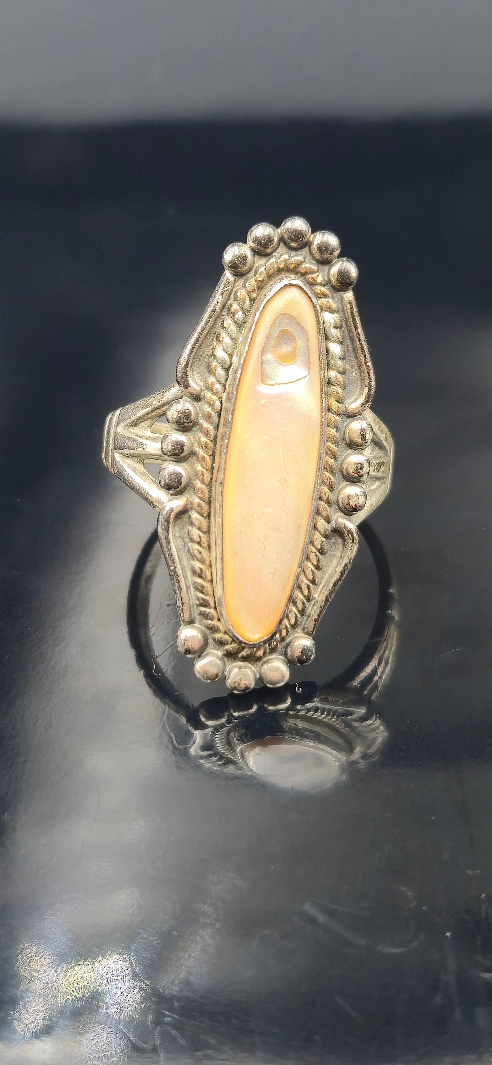 Vintage Navajo Sterling Shell Ring Sz 9 – 7.8g, Signed: Vintage Navajo sterling silver ring featuring an elongated bezel-set shell cabochon with warm cream and peach tones, highlighted by natural iridescence. The stone is framed by a rope border, bead appl