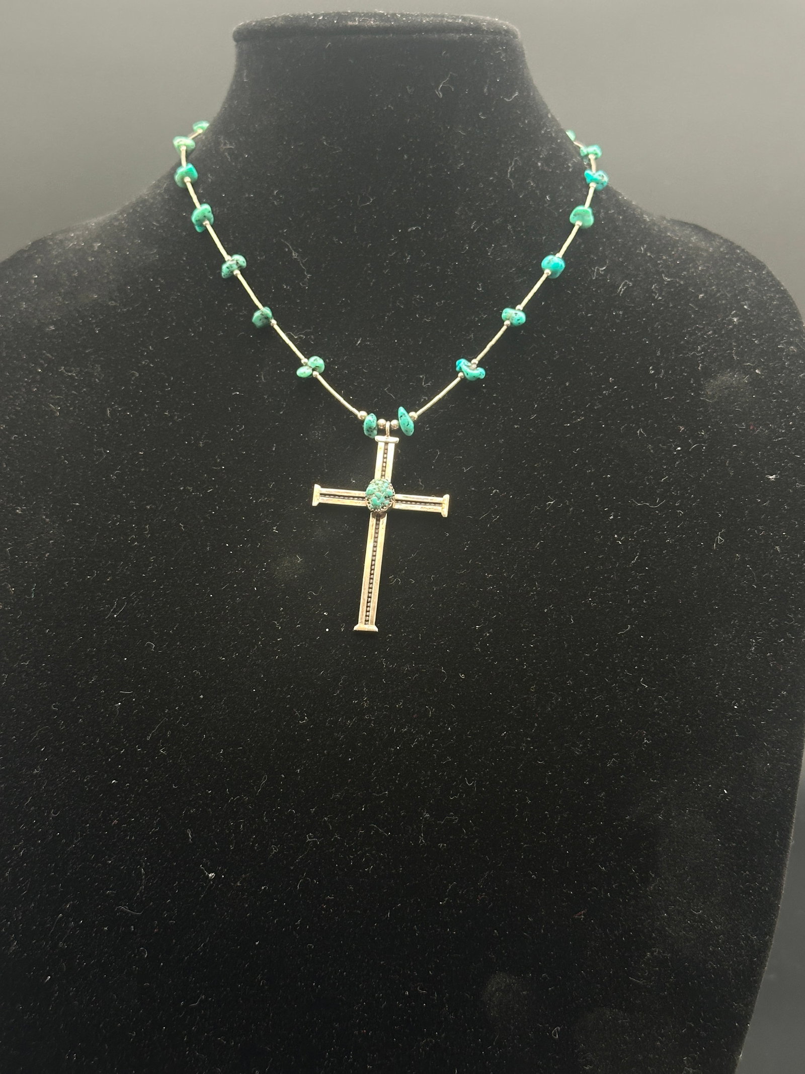 Vintage Cross Pendant Necklace with Turquoise Beads: Vintage cross pendant necklace featuring a polished cross with a central rough turquoise cabochon. The chain is accented with small turquoise nugget beads for a Southwestern-inspired look. Likely base